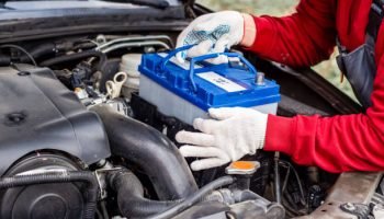 a car mechanic installs a battery in a car. Battery replacement and repair.