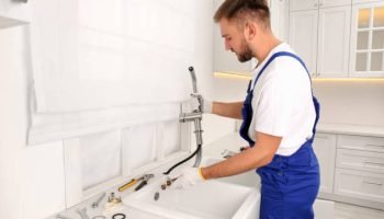 Professional plumber repairing water tap in kitchen